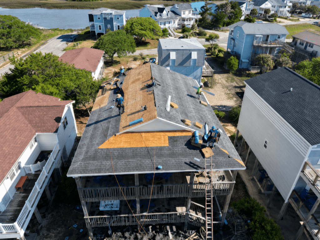 Editorial illustration of roofing work with exposed roof decking on a raised coastal-style house.